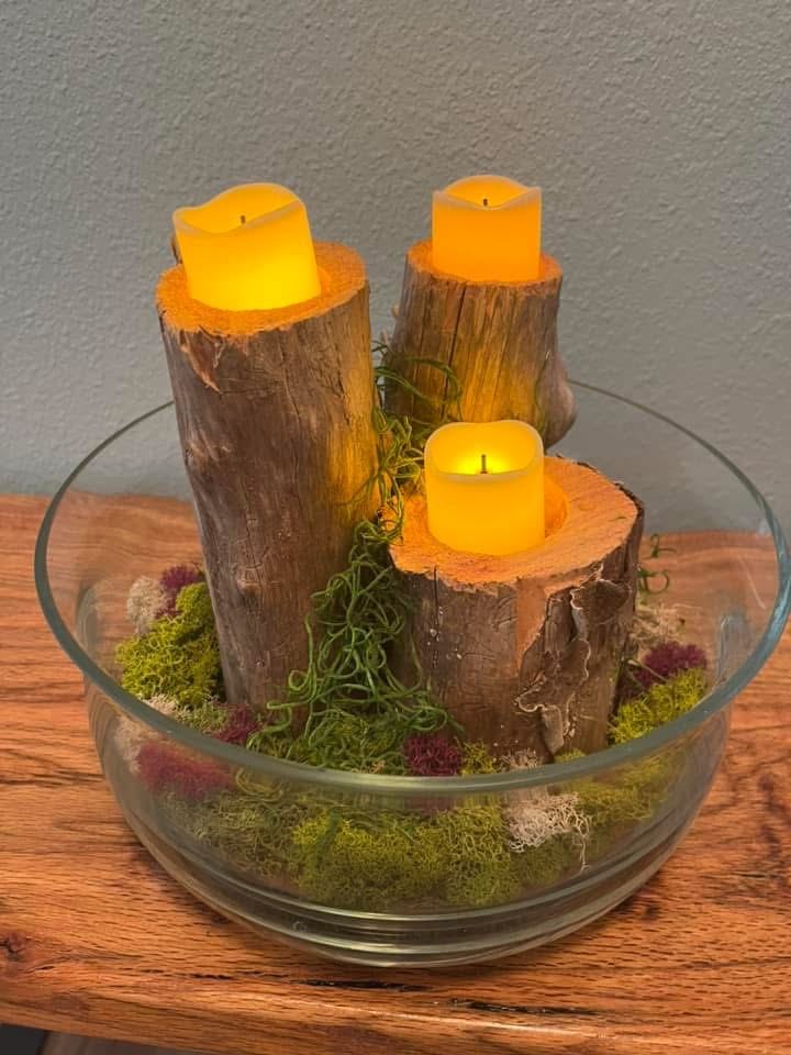 Log candle holders in a glass bowl with moss