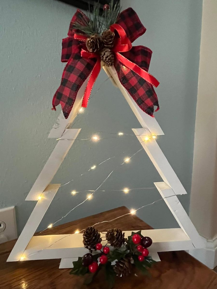White wooden Christmas tree frame with lights and a plaid bow